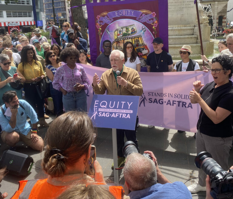 Speaker behind the podium addressing demonstrators at Equity Union’s SAG-AFTRA solidarity demonstration.