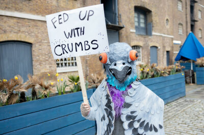London Museum member dressed as a pigeon holding placard reading 