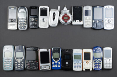 A lot of old used mobile phones with keyboards, Various brands. Many types and generations of mobile smartphone gadgets in row. Editorial